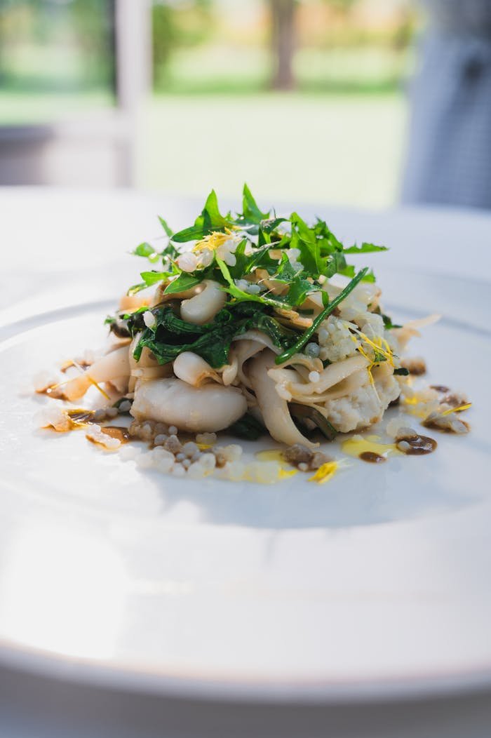 Close-up of a delicious gourmet pasta dish topped with fresh arugula and herbs, perfect for food enthusiasts.